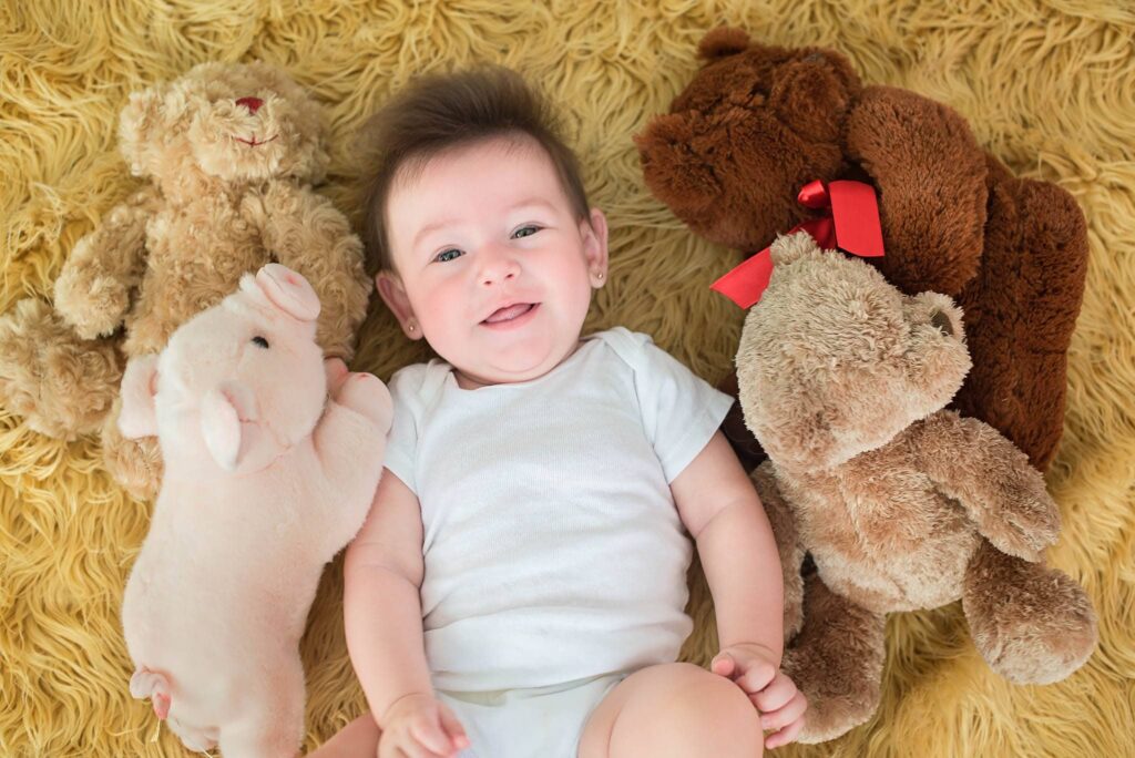 baby with stuffed animals laying down on the floor