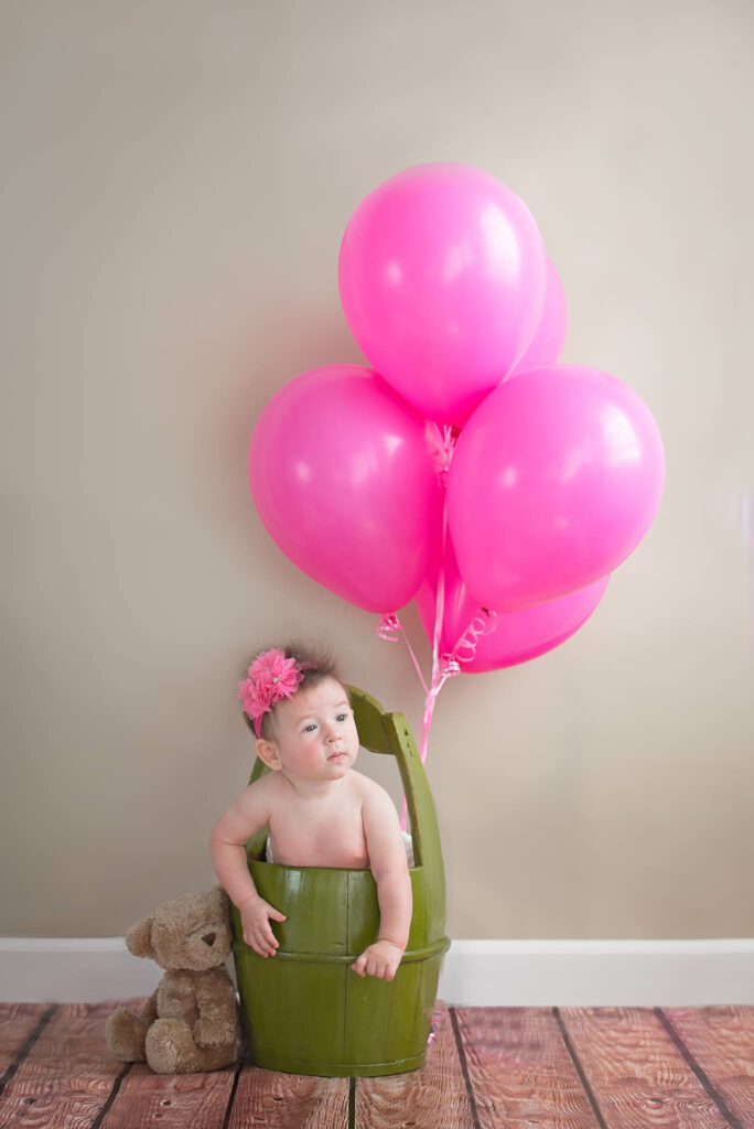 baby on green bucket with pink ballons