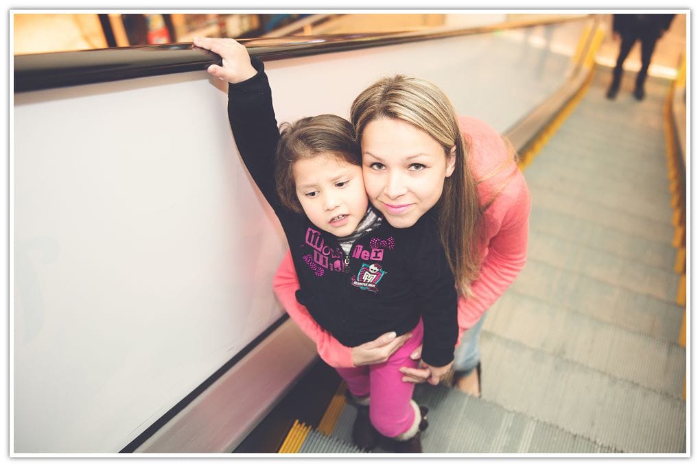 Mother and daughter going up on escalator at the mall