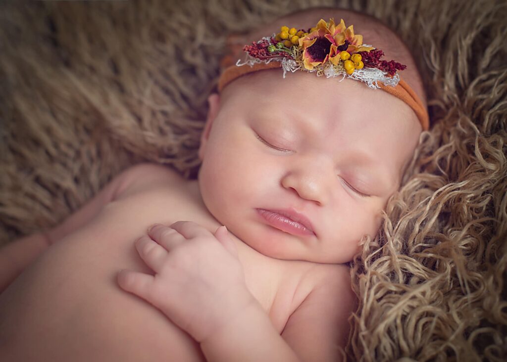 newborn with orange headband sleeping
