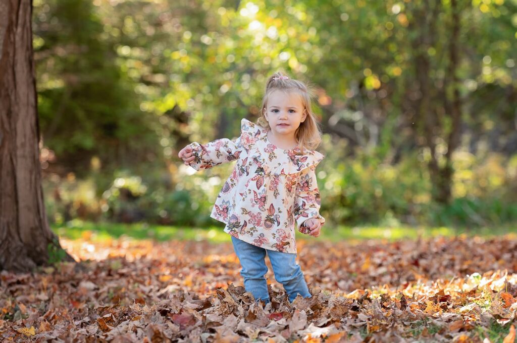 a little girl standing in leaves