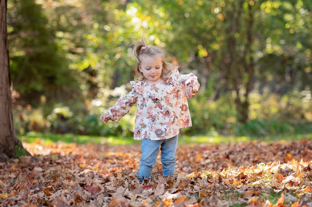 a girl standing in leaves