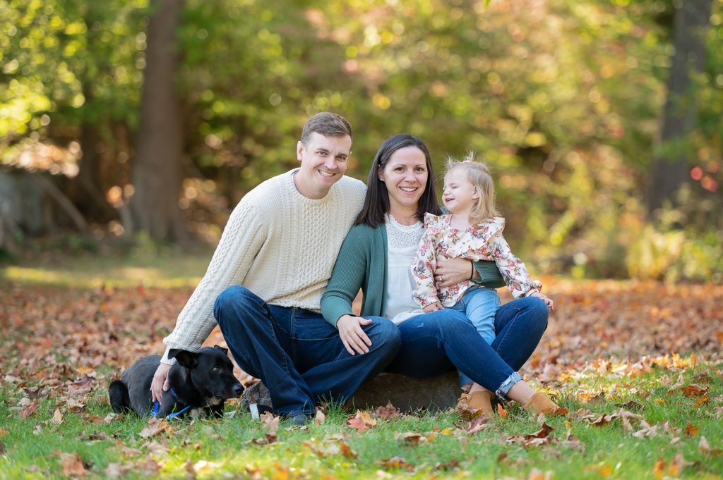 a man and woman sitting on a rock with a dog and a child