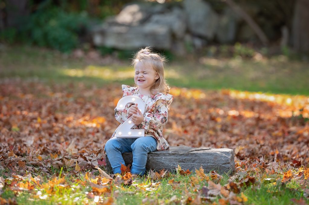 a girl sitting on a log with a lit up number two