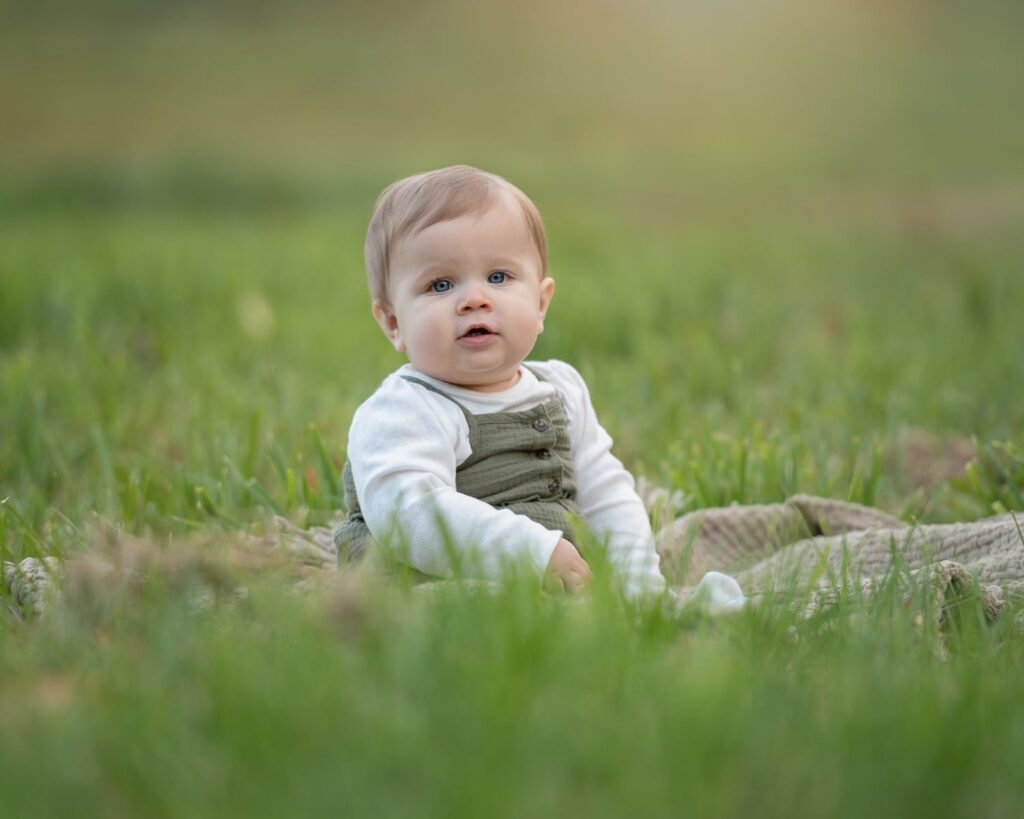 a baby sitting in grass