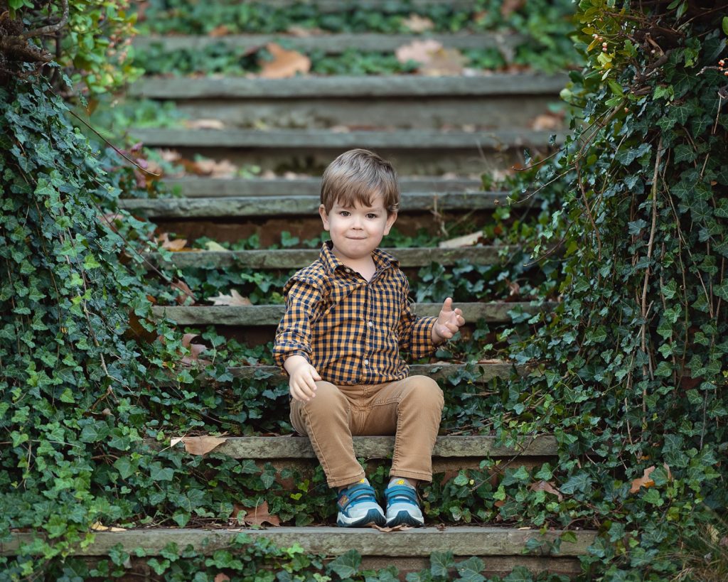 a boy sitting on stairs with ivy
