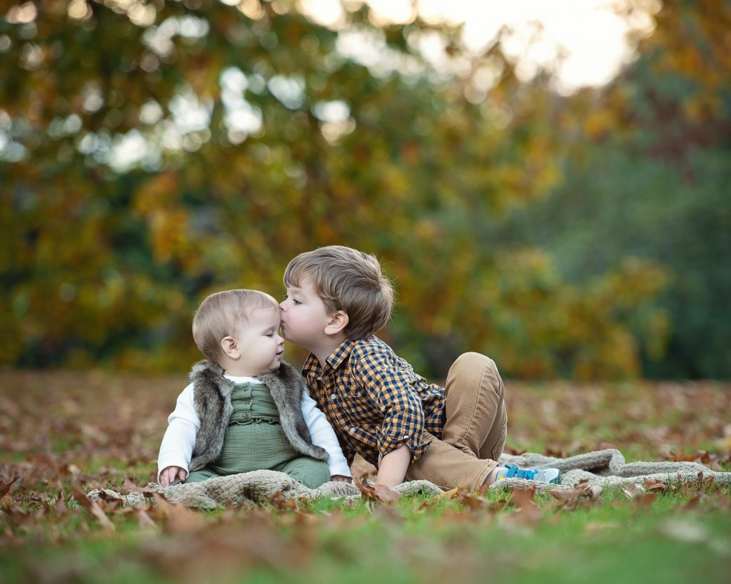 a boy kissing a baby on the cheek