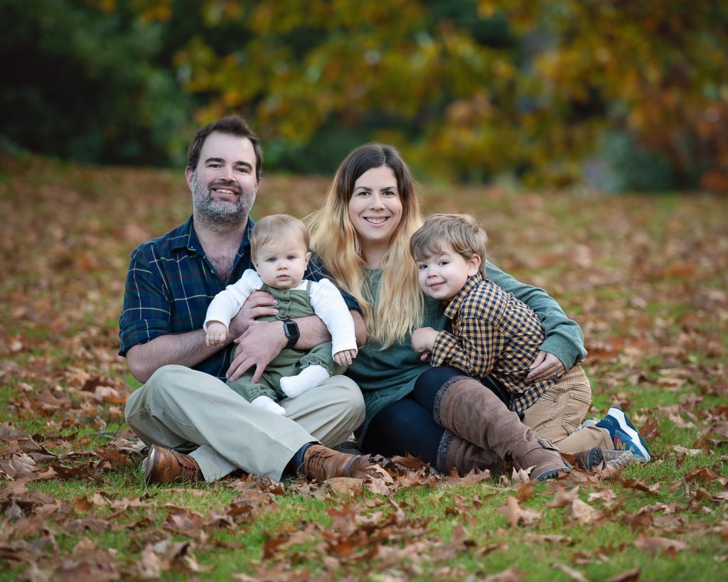 a man and woman sitting in the grass with two children