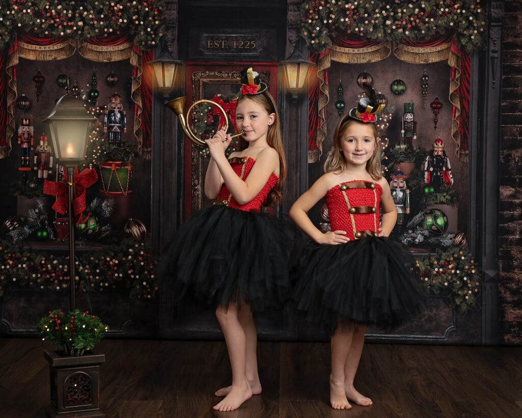 two girls in tutu skirts and hats playing a horn